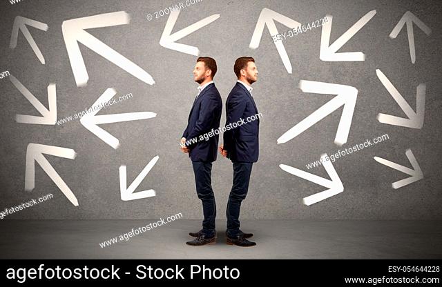 Young conflicted businessman choosing between two directions with arrows around him