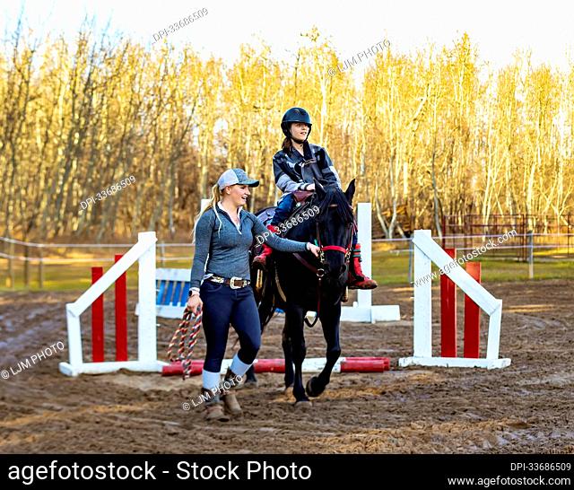 A trainer working with a young girl with Cerebral Palsy during a Hippotherapy session; Westlock, Alberta, Canada