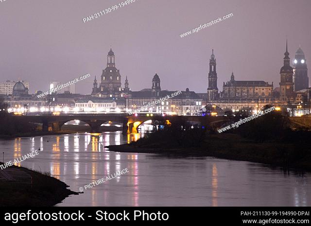 30 November 2021, Saxony, Dresden: Brightly lit is the backdrop of Dresden's old town with the Frauenkirche (l-r), the Ständehaus, the Catholic Hofkirche
