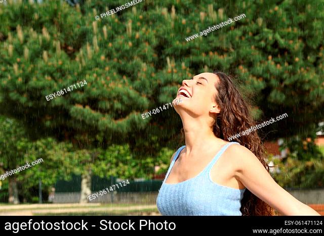 Happy woman breathing fresh air under rain in a park