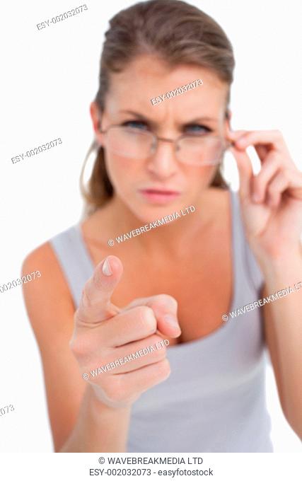 Portrait of an angry woman with glasses pointing at the viewer against a white background