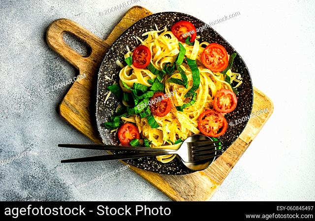 Traditional italian pasta with tomatoes and spinach on stone background with copy space