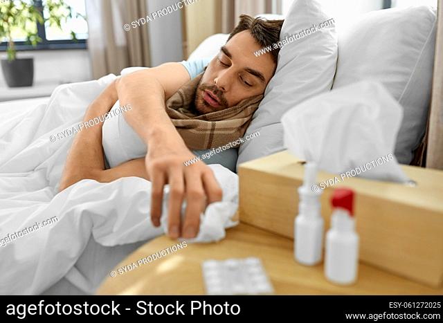sick man lying in bed and taking tissue from table
