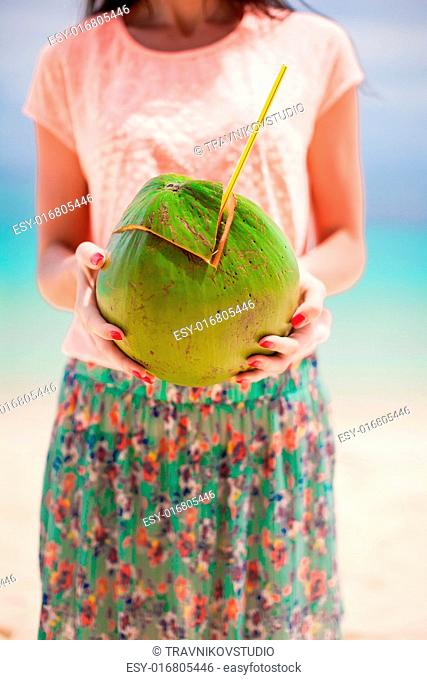 Closeup green big coconut in hands of young woman