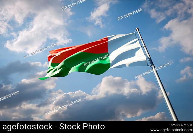 Beautiful national state flag of Madacascar fluttering at sky background. Low angle close-up Madacascar flag 3D artwork