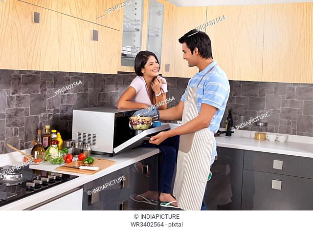 Indian couple preparing food together in kitchen