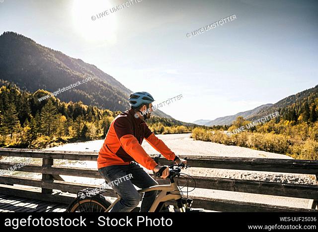 Man wearing helmet cycling on bridge