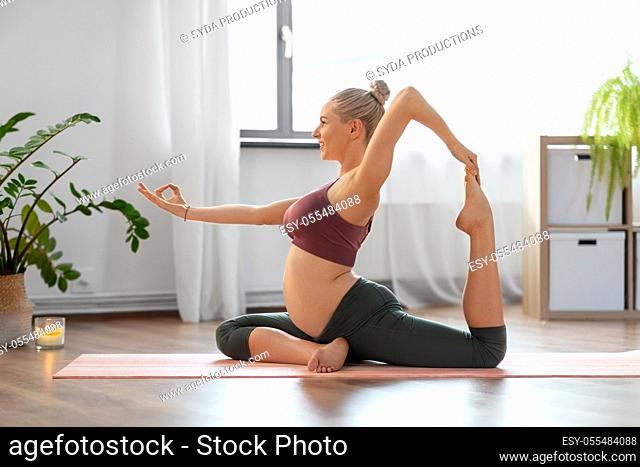 happy pregnant woman doing yoga at home