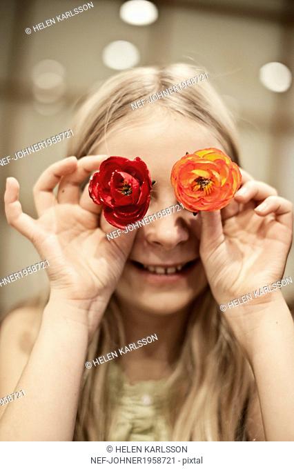 Girl covering her eyes with flowers