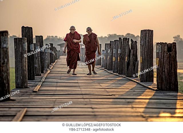 Two Buddhist monks walk along the U Bein bridge at sunrise, Amarapura, Myanmar