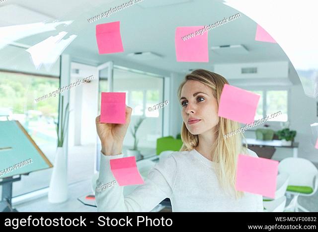 Blond businesswoman writing ideas on adhesive note in office