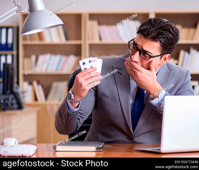The businessman gambling playing cards at work