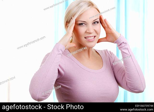 Blonde Frau mit Kopfschmerzen in der Wohnung