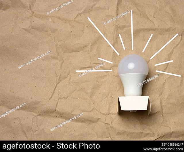 white light bulb with rays on a brown background, green energy concept, new ideas, copy space