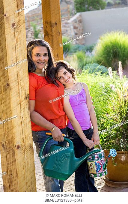 Mother and daughter watering plants outdoors