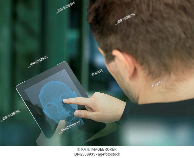 Young businessman touching an iPad with his finger, seen from behind