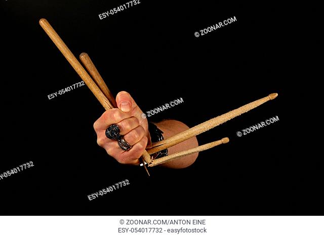 Close up man hand holding two broken drumsticks over black background, side view
