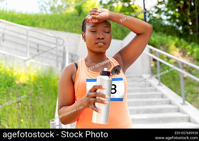 tired female marathon runner with bottle of water