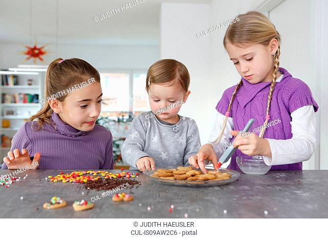 Girls at kitchen counter decorating cookies