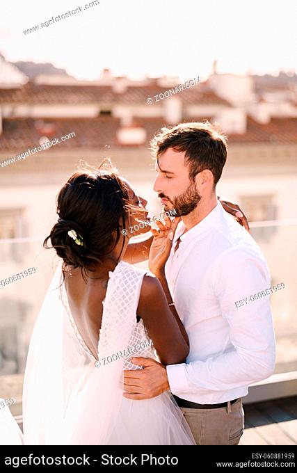 Interracial wedding couple. Destination fine-art wedding in Florence, Italy. Caucasian groom and African-American bride cuddle on the roof