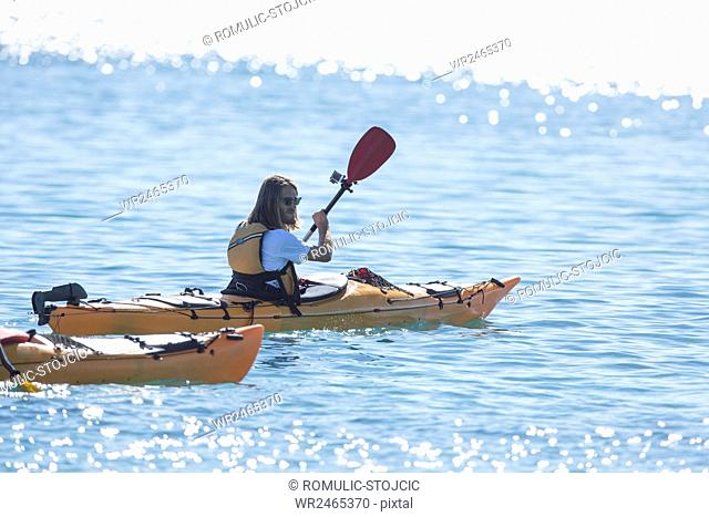 Mid adult man kayaking on river in bright sunshine
