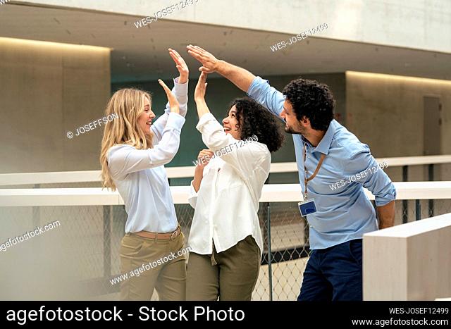 Happy business colleagues giving high-five in corridor