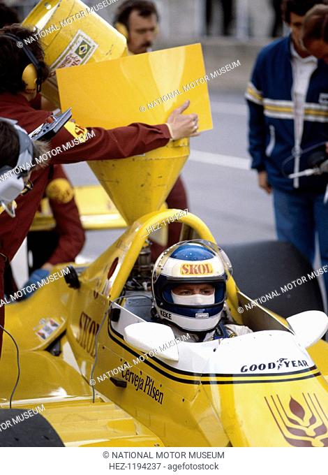 Keke Rosberg in a Fittipaldi-Cosworth F7, British Grand Prix, Brands Hatch, 1980. In the pits during a fuel stop. A technician pours the fuel into the back of...