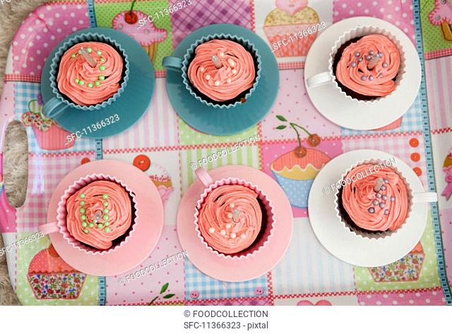 Pink cupcakes with birthday candles served in cups