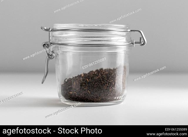 close up of jar with black tea on white table