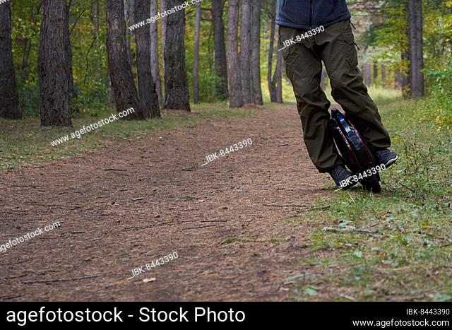 Front view of male legs on a unicycle in the forest