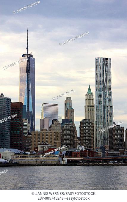 Freedom Tower construction and Gehry Tower in downtown Manhattan set against evening clouds as seen from across the East River in Brooklyn, NY, USA