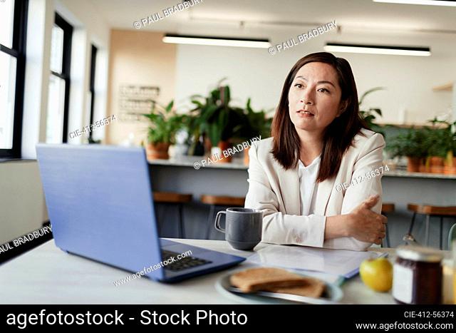 Thoughtful businesswoman working at laptop in office