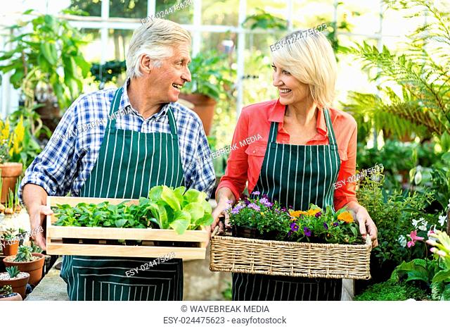 Couple holding plant crates at greenhouse