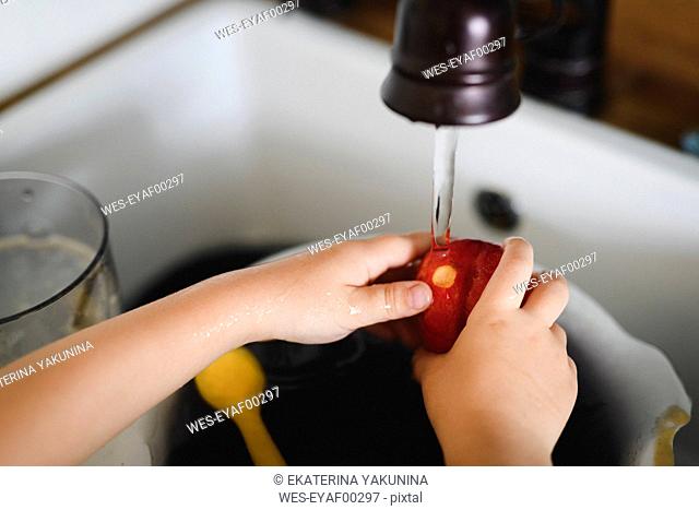 Little boy's hands washing peach in the kitchen, close-up