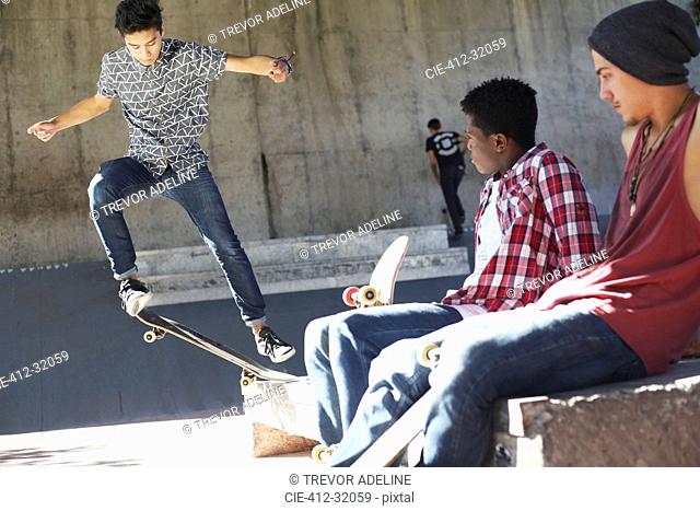 Friends watching teenage boy doing stunt at skate park