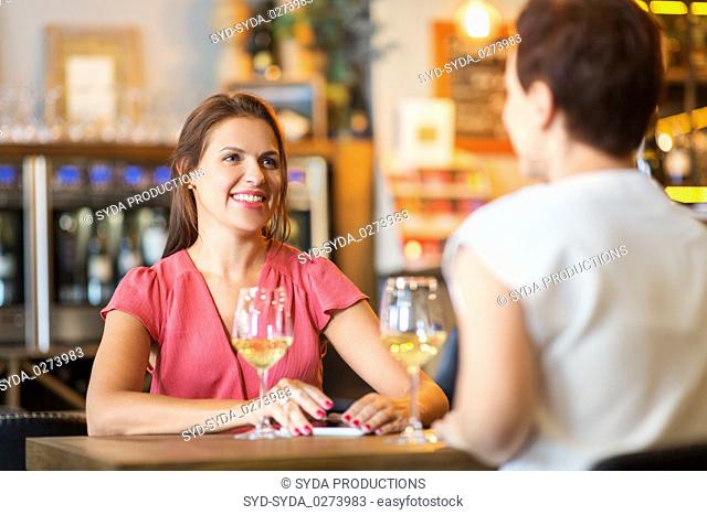 happy women drinking wine at bar or restaurant