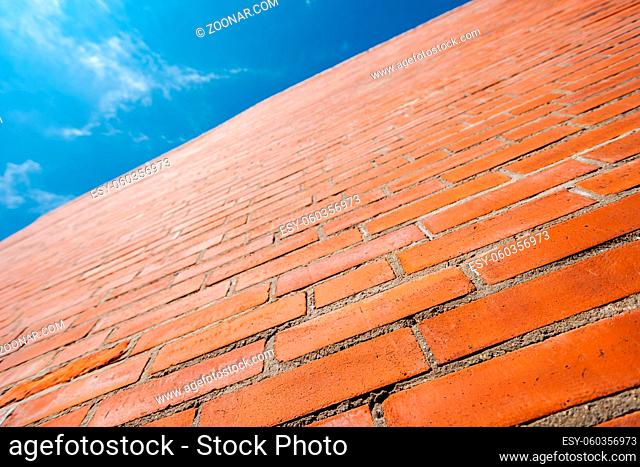 Looking up at giant new red brick wall with cloudy blue sky