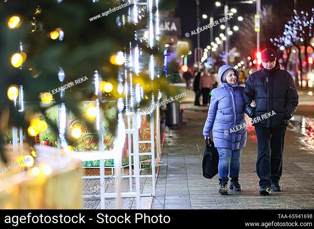 RUSSIA, LUGANSK - DECEMBER 20, 2023: A couple stroll past Christmas decorations glowing on Sovetskaya Street. Alexander Reka/TASS