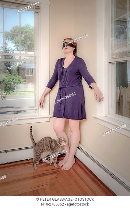 Young blindfolded woman and her cat in the living room
