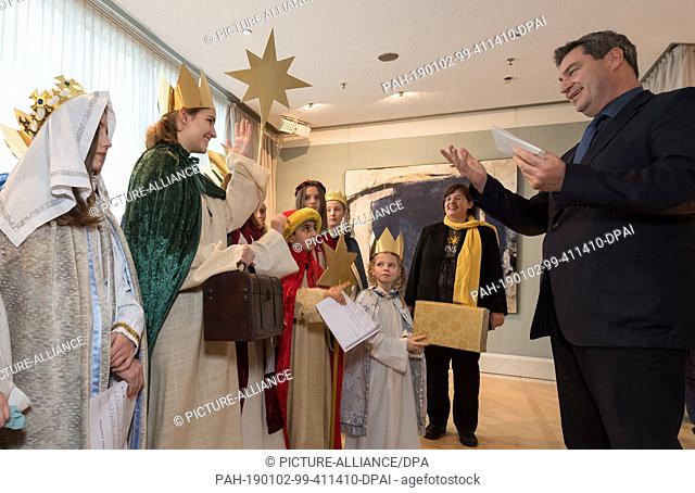 02 January 2019, Bavaria, München: The Bavarian Prime Minister Markus Söder (CSU) presents envelopes with donations to the star singers present in the Bavarian...