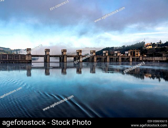 Solid structure of the Crestuma Lever dam on River Douro in Portugal reflected in calm water