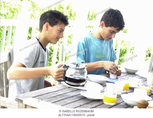 Two teenage boys having breakfast outside