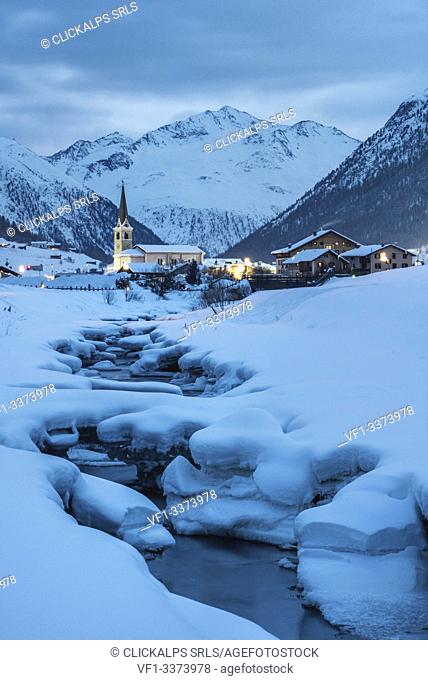 The church of Livigno and frozen river in a cold evening of winter, Province of Sondrio, Valtellina, Lombardy, Italy, Europe