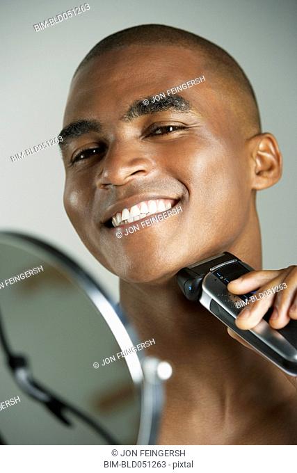 African man shaving with electric razor