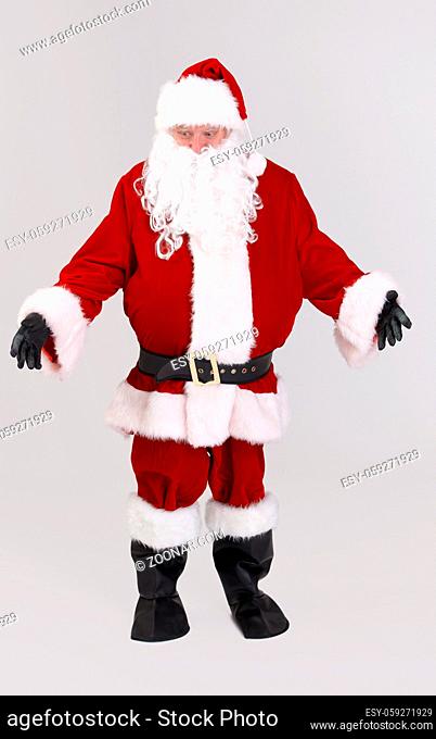 Full size portrait of Santa outspreading arms, looking down, isolated on gray background