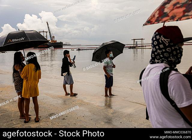 People take pictures as they flock to a portion of Manila baywalk area that was covered with crushed dolomite rocks amid rising coronavirus cases in Manila