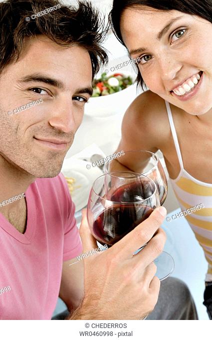 Portrait of a young couple toasting with wine glasses at the kitchen counter