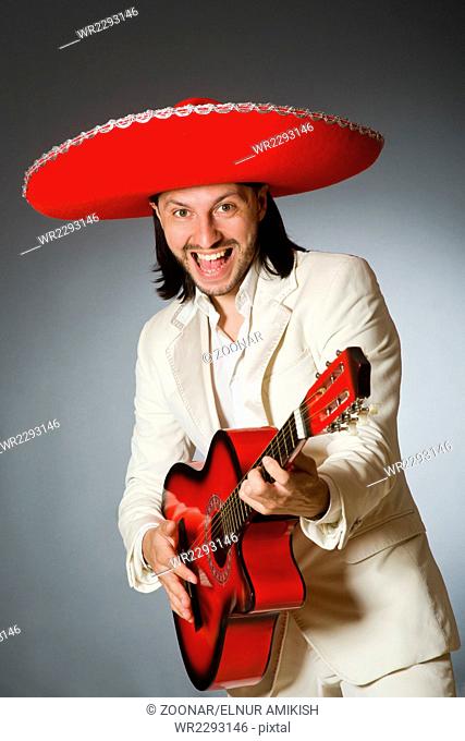 Funny mexican in suit holding guitar against gray