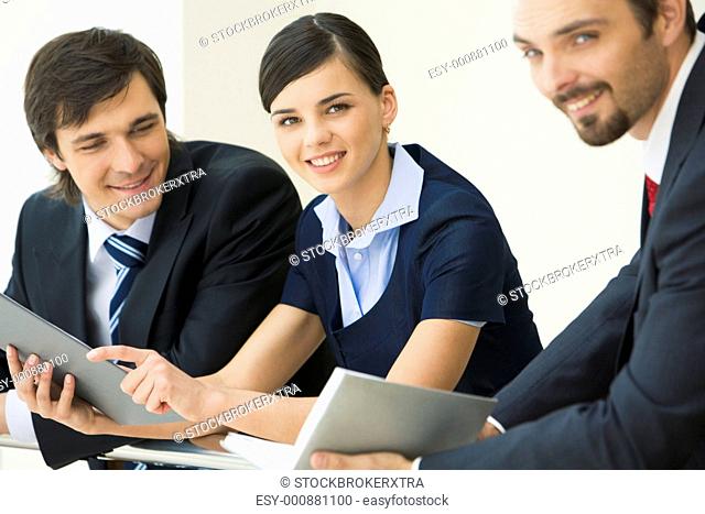Pretty business lady looking at camera with smile surrounded by her co-workers