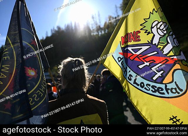 07 October 2022, Hesse, Helsa: An environmental activist carries a flag in protest at the opening of the A44 highway section between Helsa and Hessisch...